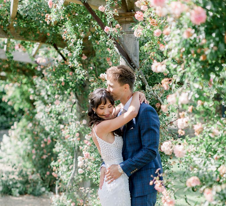 bride in a fitted appliqué wedding dress kissing her groom in a navy check suit at their Euridge Manor Italian themed wedding 