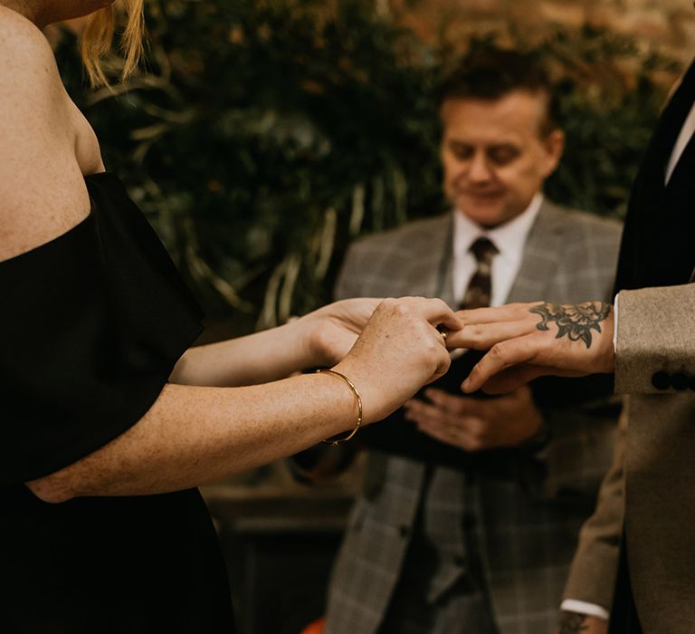 The bride slides the wedding ring onto the groom's finger for their wedding ceremony 