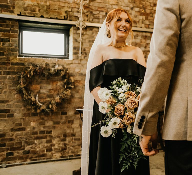 Bride wearing a black bias satin off the shoulder wedding dress with cascading bouquet 