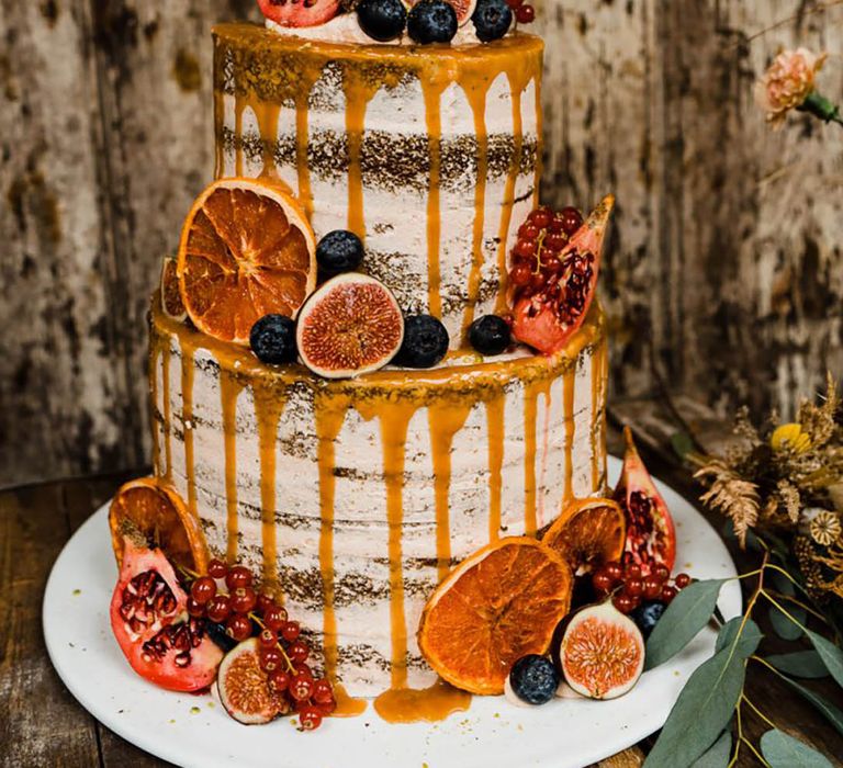 Two tier semi-rustic naked wedding cake with orange drip icing with passionfruit, pomegranate, and more 