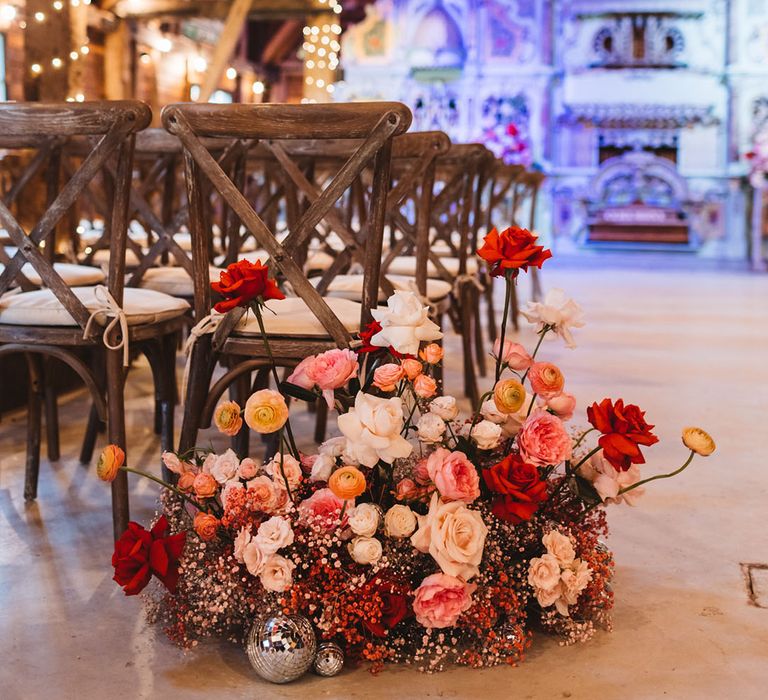 Pink and red gypsophila, ranunculus, and rose wedding aisle flower decorations at Preston Court 