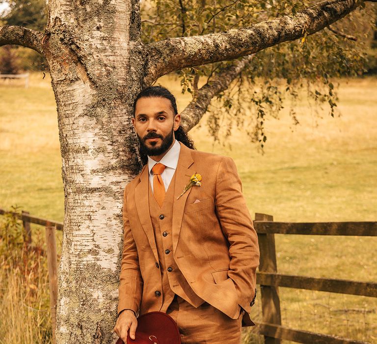 Groom in warm tone brown wedding suit at wedding 