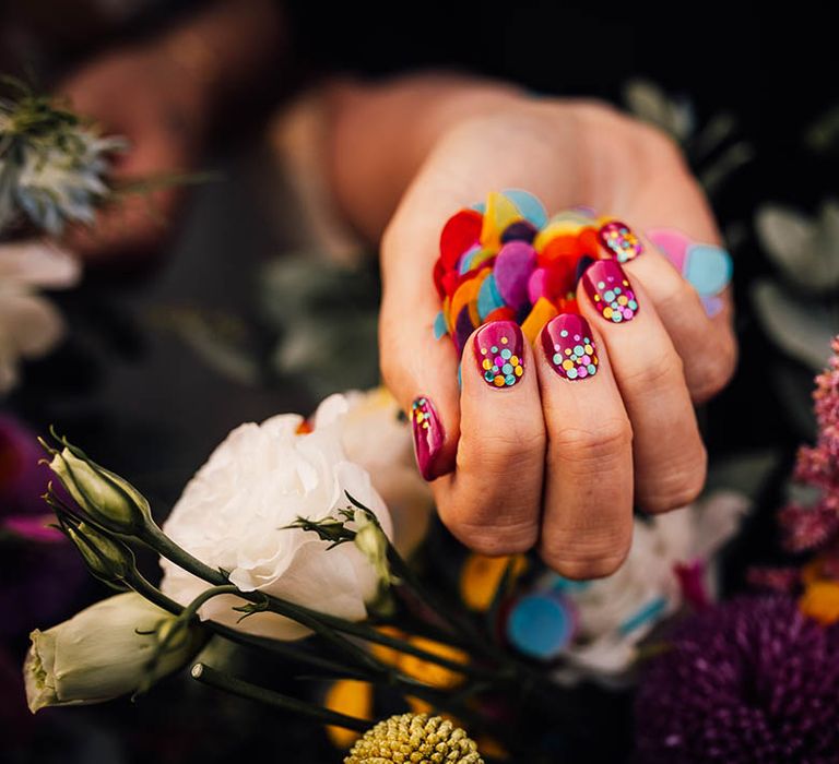 Bride with dark pink wedding nails with sparkly coloured sequins to match the bright wedding confetti 