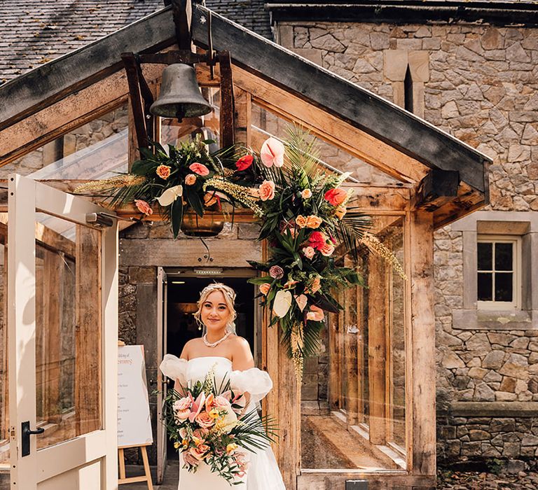 Wyresdale Park wedding with the bride in a puff sleeve gown carrying a tropical flower wedding bouquet with palm leaves and anthuriums 