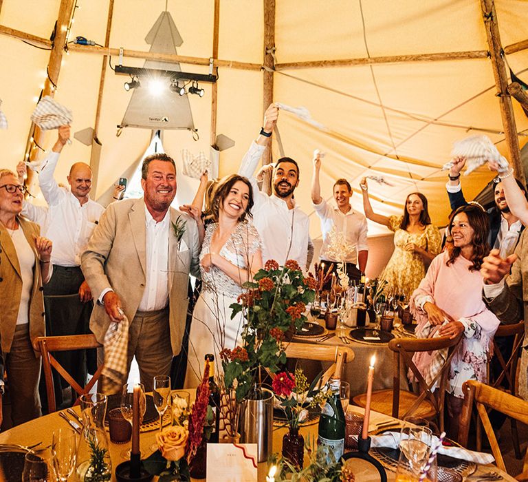 The guests stand and wave their napkins to greet and celebrate the bride and groom 