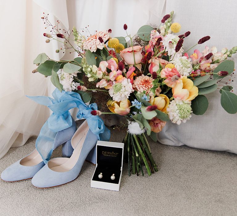 Block heel blue wedding shoes with ribbon with colourful wildflower wedding bouquet and pearl earrings 