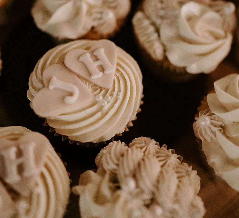 White iced wedding cupcakes from the dessert table with heart and pearl decorations 