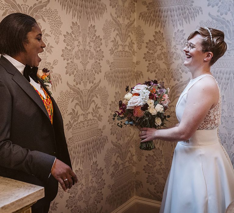 The two brides react to seeing each other in a special first look moment before the wedding ceremony 