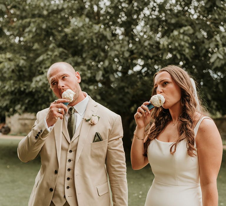 The bride and groom eat ice cream at their summer wedding 