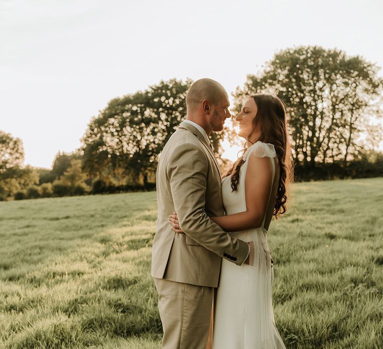 Golden hour sunset moment as the couple embrace for wedding portrait photo 