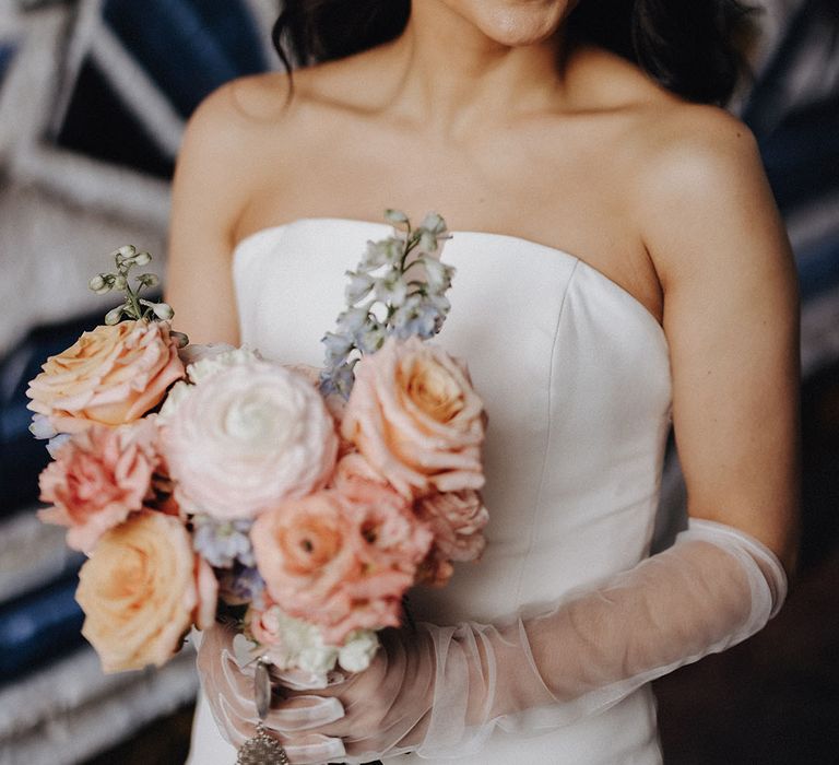 Bride in classic strapless wedding dress with pastel wedding bouquet 