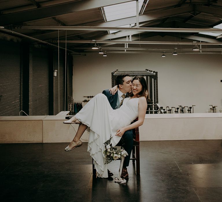 Bride sitting on her grooms lap at city wedding