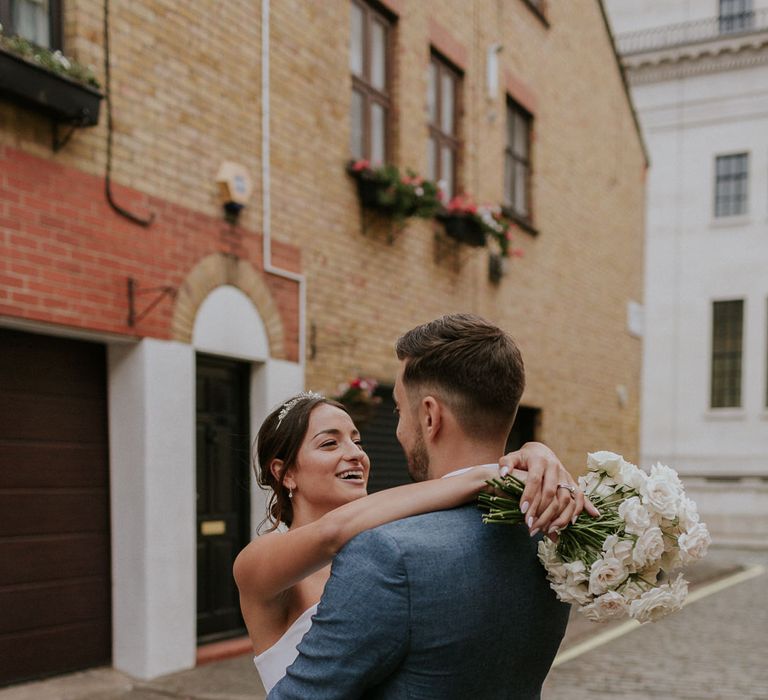 Bride embracing her groom in blue suit