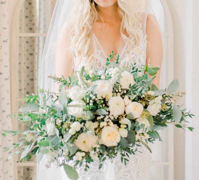 Bride in lace Made With Love wedding dress holding a white and green bouquet 