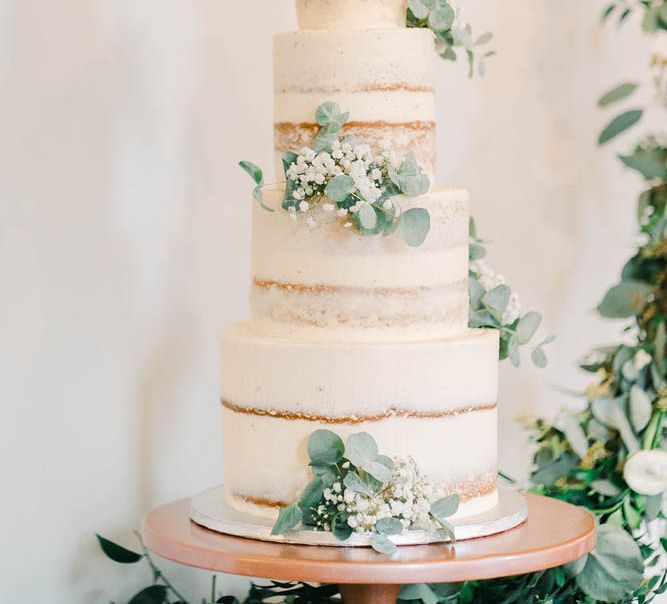 Semi naked wedding cake with white and green floral decor 