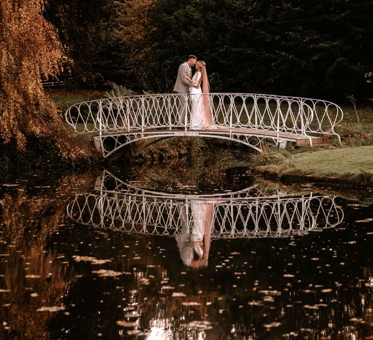 Bride and groom on the lakeside bridge at Preston Court