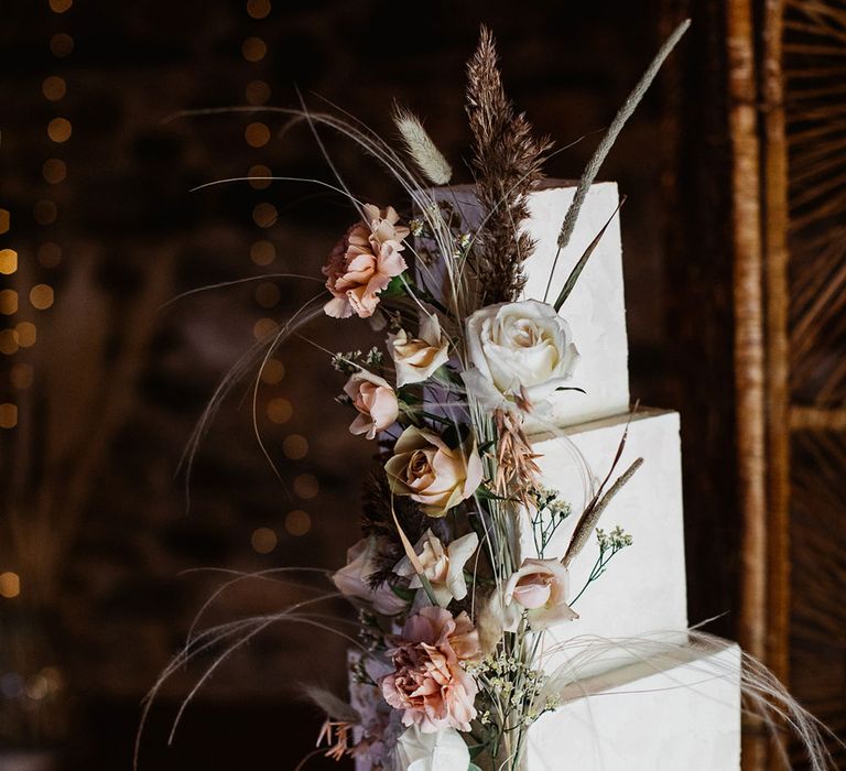 White box three tiered wedding cake with floral rose and grass decoration