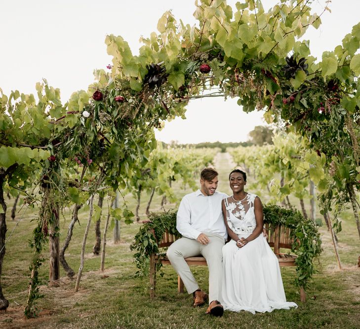 Black bride with short hair wearing bridal separates and feather earrings in a vineyard in the U.K