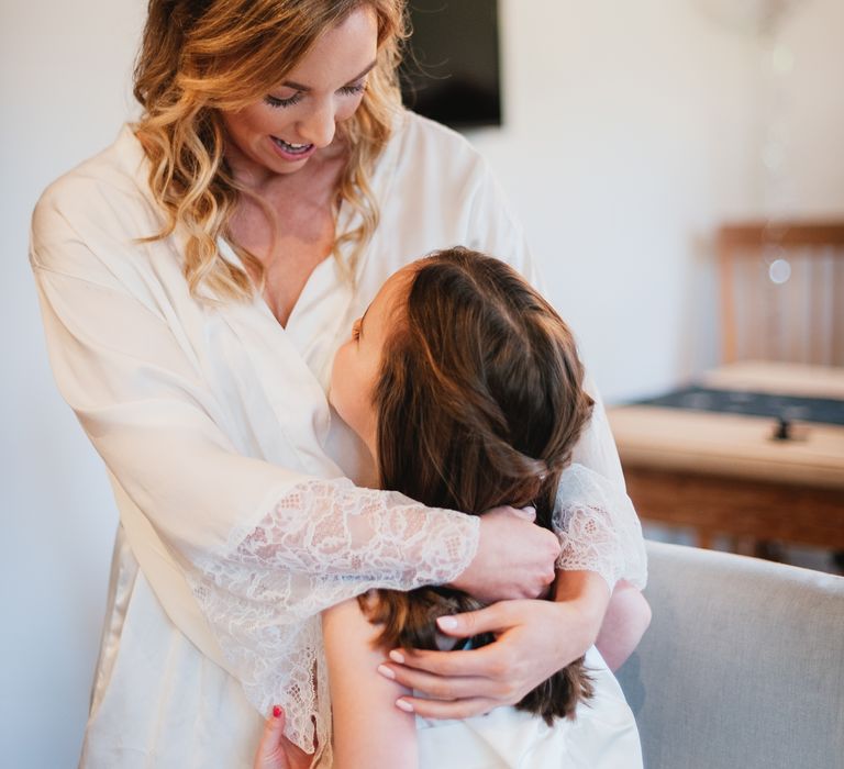 Bride cuddles flower girl on the morning of her wedding