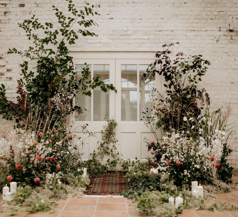 Wedding ceremony flowers at Our Beautiful Glasshouse in Sussex with wool rug 