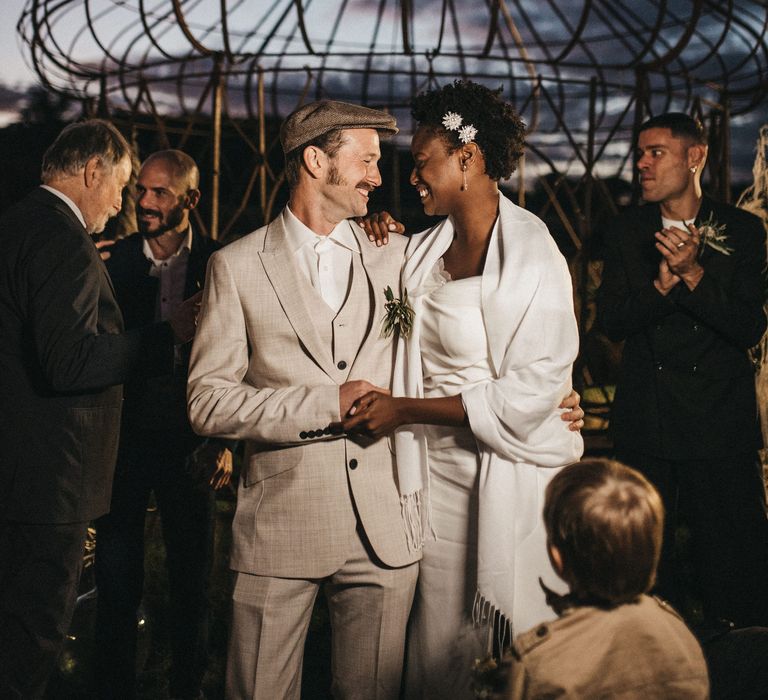 Portrait of the Groom in a beige Peaky Blinders wedding suit and flat cap with his bride in a Georges Hobeika wedding dress and wrap 