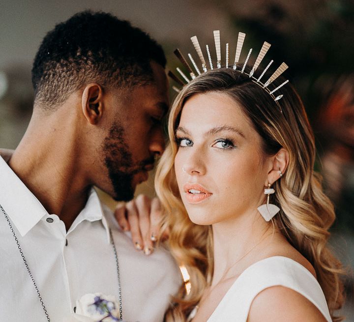 bride in a gold crown with nail art wearing dangling earrings and peach lipstick 