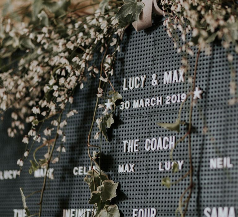 Dark grey DIY pinboard seating chart with foliage decor at Caswell House wedding