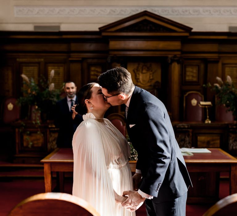 Bride and groom kissing at the altar during their town hall wedding ceremony 