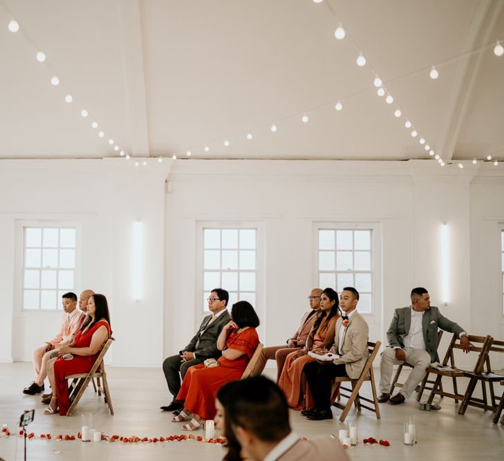 Intimate Core Clapton wedding with guests sitting on wooden chairs at the ceremony 