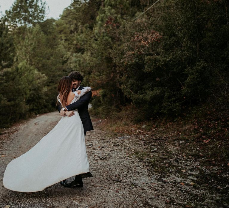 The groom swings the bride around, her dress flowing in the breeze