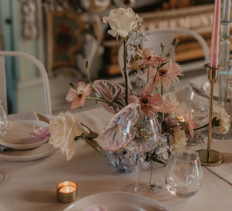 Place setting white white plates and linen and iridescent wine glasses 