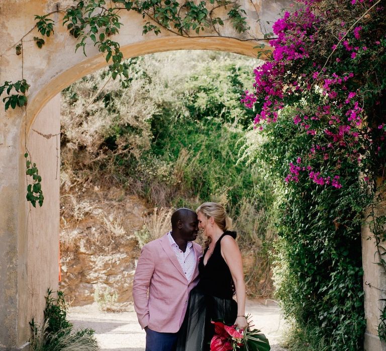 Groom in pink dinner jacket with bride in Vera Wang black wedding dress