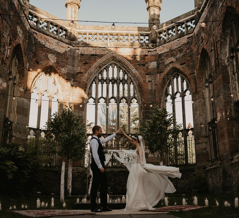 Bride and groom dancing on rugs under festoon lights at St Lukes Bombed Out Church in Liverpool 