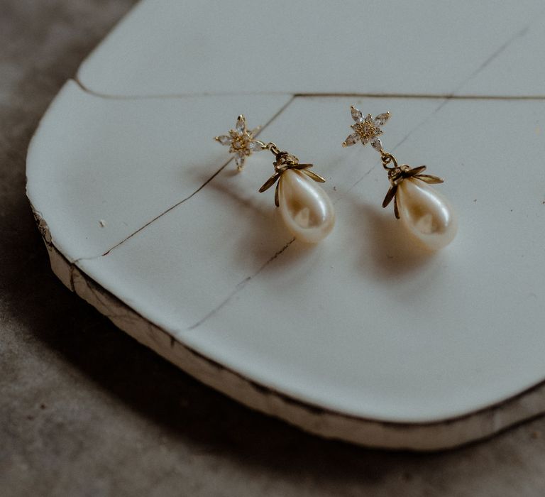 Pearl drop earrings sit in a display dish. 