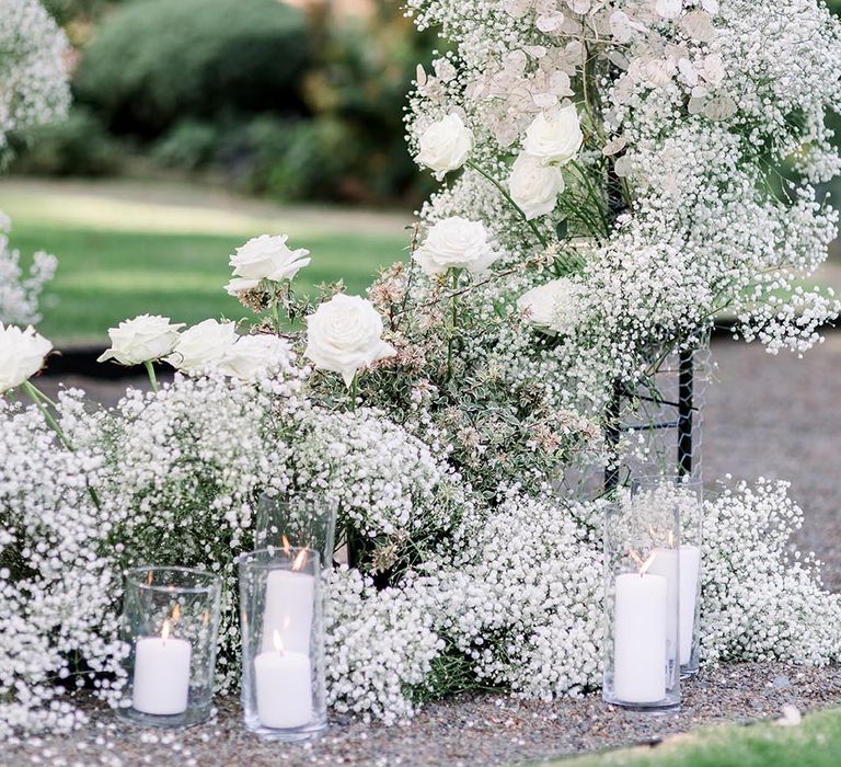 Gypsophila and white rose floral arch and pillar candles in cylinders 