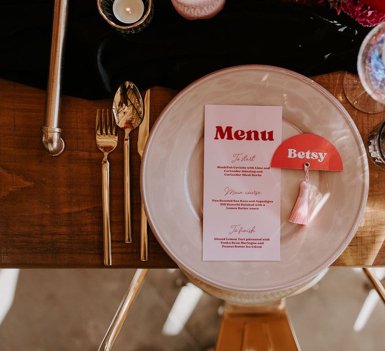 Place setting with contemporary menu card, gold cutlery and iridescent glassware 