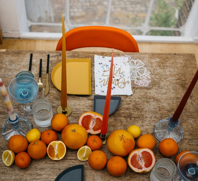 Minimal, retro inspired tablescape with gold, orange and mustard tones. Including citrus fruit centrepiece decoration and tapered candles