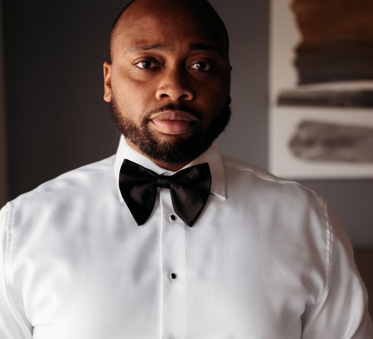 African American black groom wears white shirt with black bow tie on the morning of his wedding day