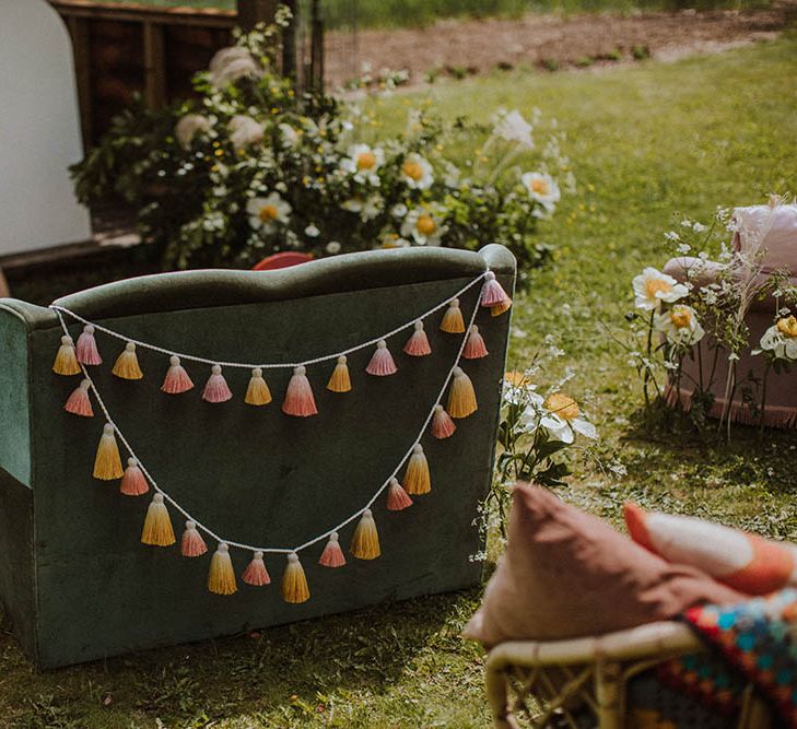 Green velvet retro sofa decorated with blush tissue tassels for sixties wedding