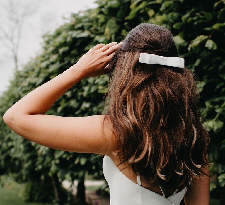 Bride with half up half down wedding hair and tiny bow hair accessory 