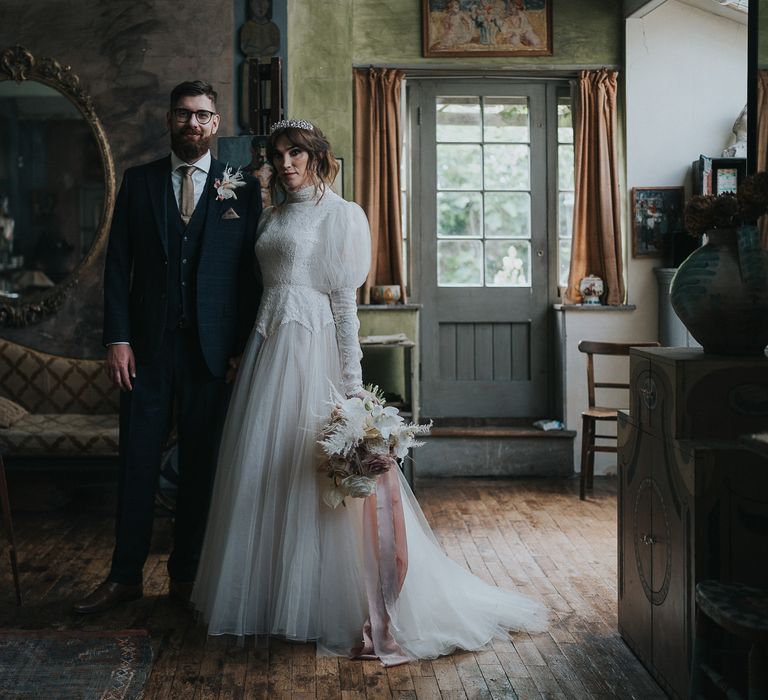 Bride & groom stand together in rustic art deco room for post-wedding couples portraits