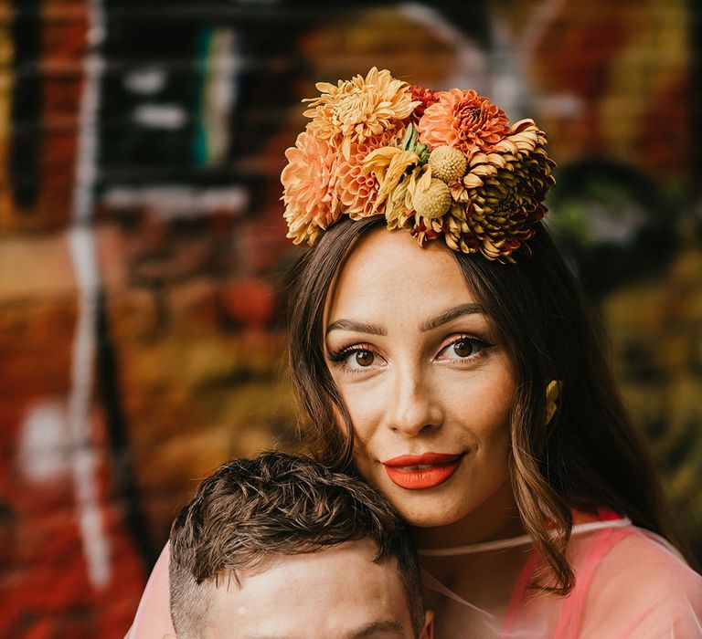 Bride in a Frida Kahlo flower crown with winged eyeliner and red lipstick embracing her disabled groom at their Shoreditch elopement 