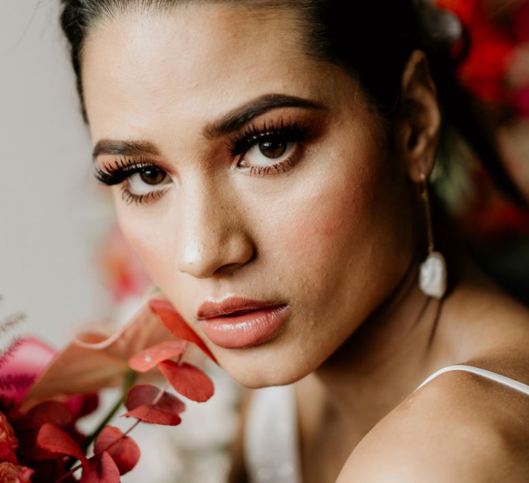 Bride with brunette hair tied up in a ponytail with light brown lipstick and fluttering eyelashes 