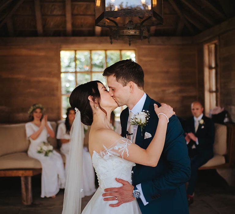 Bride & groom kiss on their wedding day as brides veil falls behind her