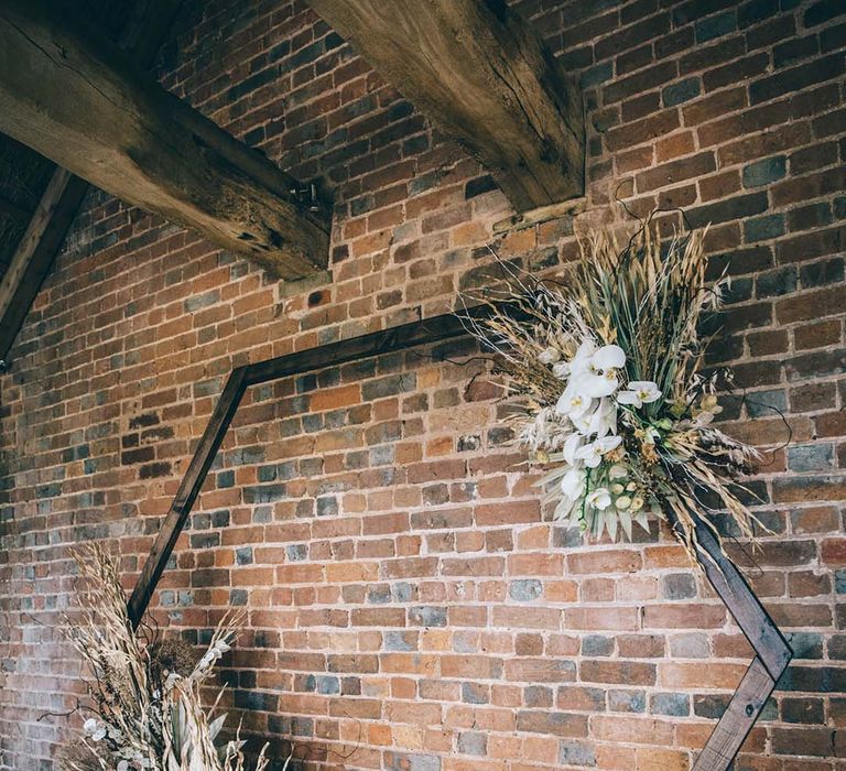 Wooden hexagonal altar decorated with dried flowers in front of an exposed brick wall at Brickhouse Vineyard, Devon