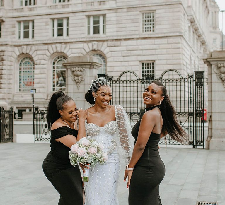 Bride dances with her bridesmaids who wear sleek black bridal gowns