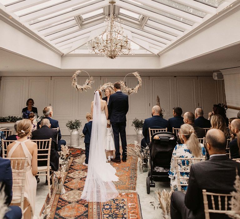 Bride & groom during wedding ceremony as guests watch on