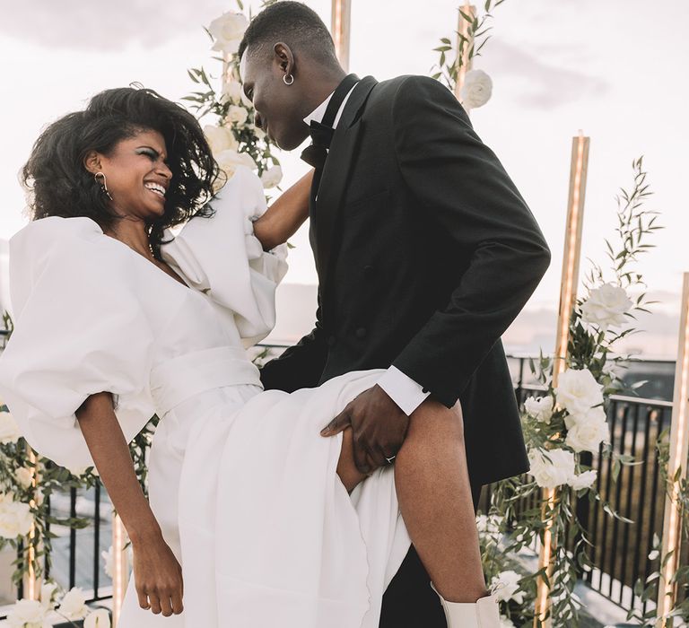 Fun bride and groom portraits at their rooftop Paris elopement with bride in a puff sleeve wedding dress and white boots 