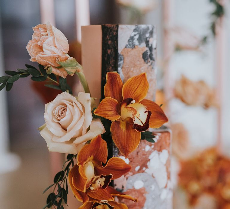 Orange and blush wedding flowers decorating the styling two tier wedding cake with marble design 