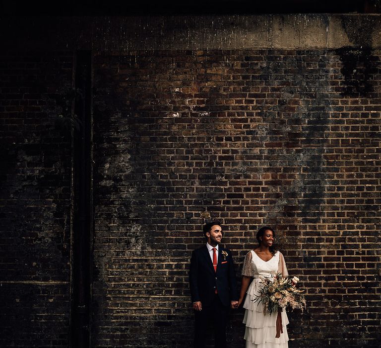 Urban wedding photograph with bride in a layered tulle wedding dress and groom in a navy suit 